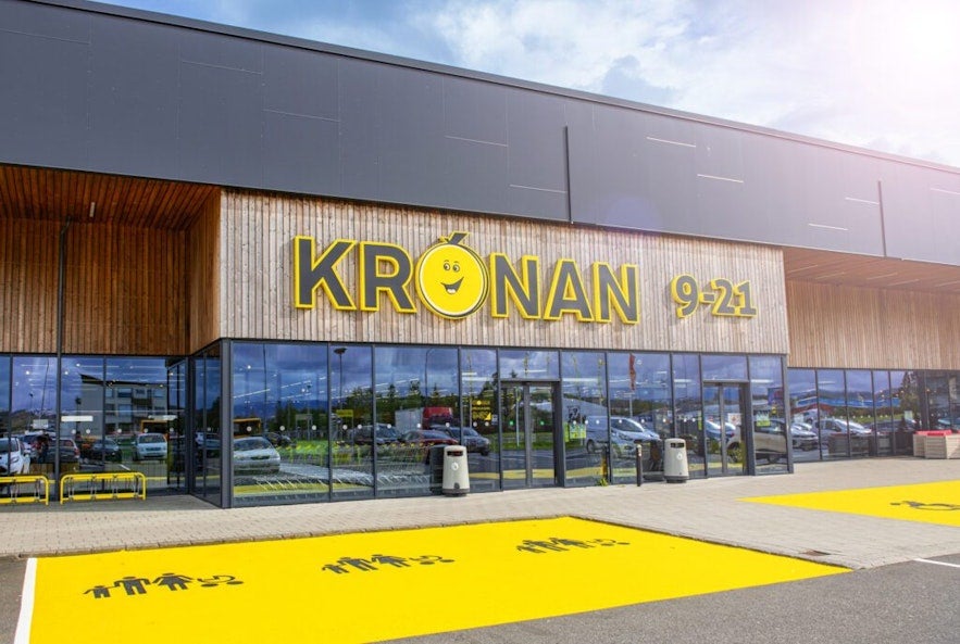 Exterior of Kronan supermarket in Iceland with bright yellow branding and customer entrance