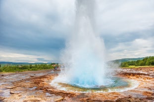 Strokkur geyser erupts with boiling water to impressive heights.