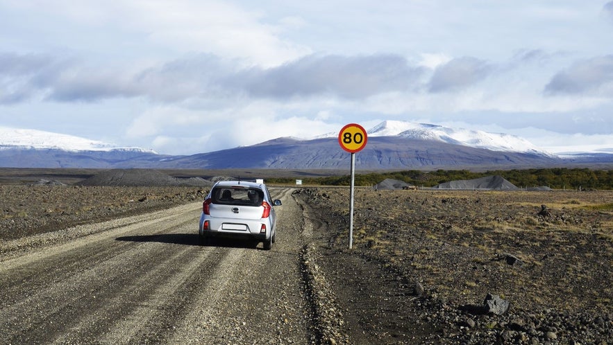 Driving in Iceland on a gravel road near Thingvellir with an 80 km/h speed limit and mountain views ahead.