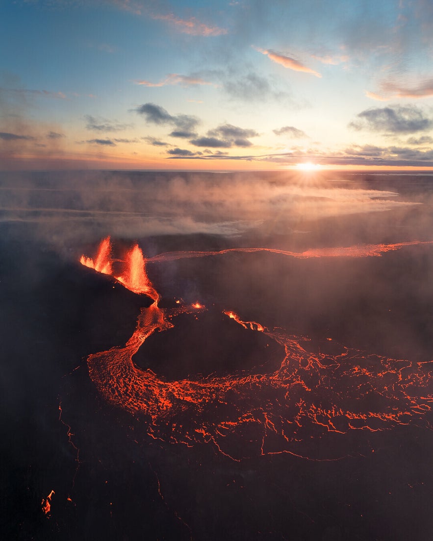 Eruption at Sundhnukagigar Volcano in Reykjanes Peninsula with glowing lava flows and smoke under a dramatic sunset sky.