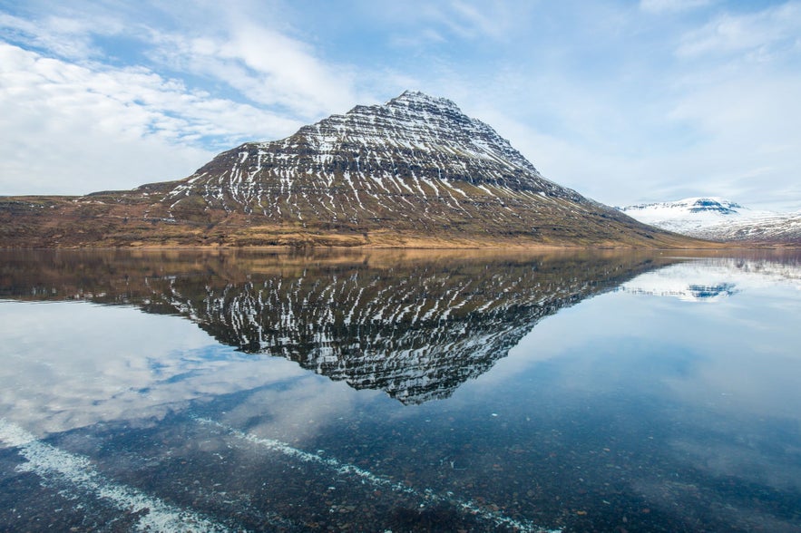 Hólmatindur mountain located in Eskifjordur East Eastfjords seen with an ocean reflection.