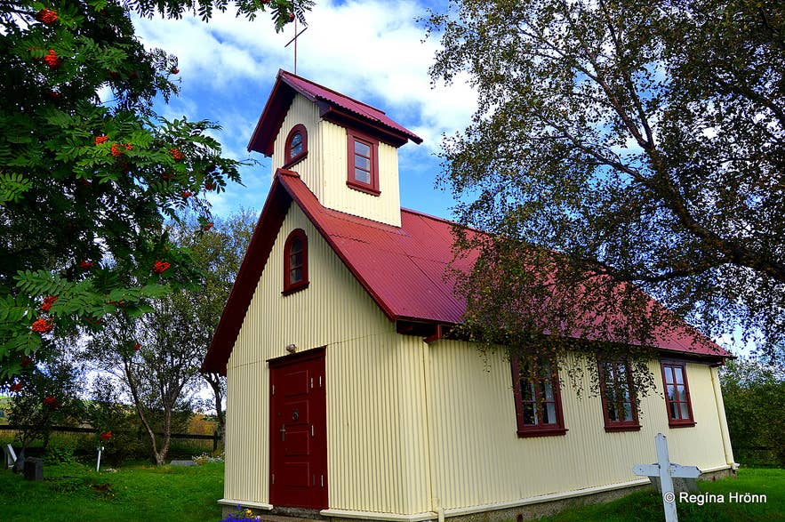 A small white church with a red roof sits among rowan trees along the Haukadalur Church loop trail.
