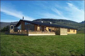 The front of Eyjar Fishing Lodge, located in East Iceland, with a blue sky.