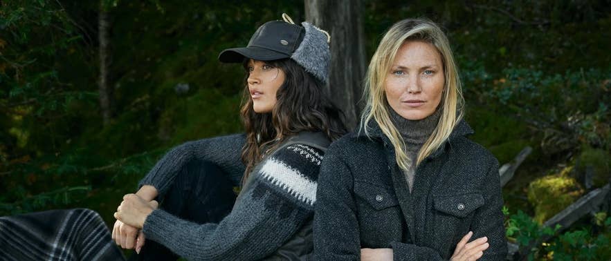 To kvinder iført stilfuldt uld- og strikketøj fra det islandske tøjmærke Farmers Market, der poserer i en skovkulisse med naturligt lys og nordisk-inspireret mode.