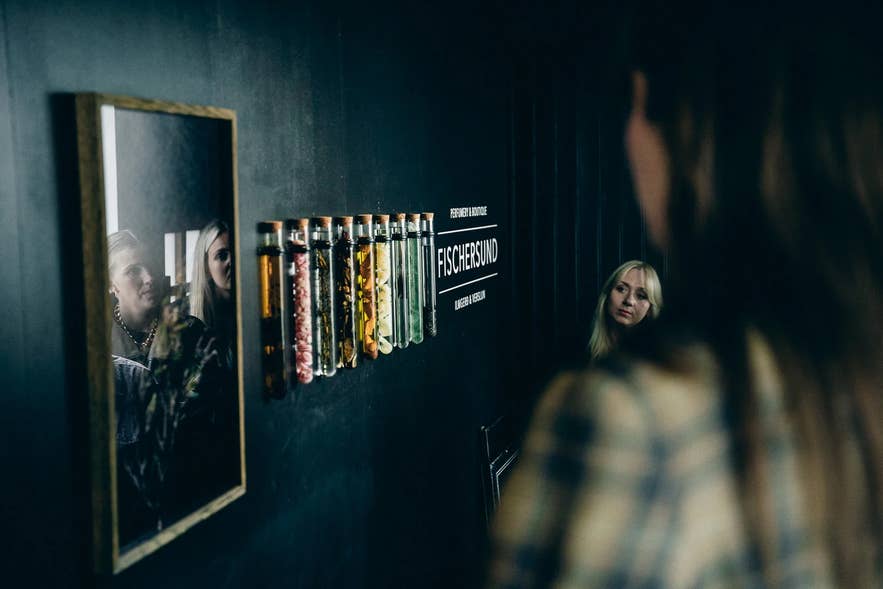 Besøgende på opdagelse i Fischer-butikken i Reykjavik, Island, hvor der er udstillet reagensglas med naturlige ingredienser i denne parfumeributik og kunstgalleri, der er kendt for sine håndlavede islandske dufte og unikke design.