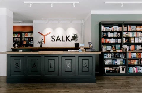 Modern interior of Salka bookstore and publishing house in Reykjavik, featuring a sleek black checkout counter and shelves filled with books.
