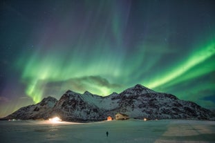 A display of the northern lights illuminate above a snow-covered mountain and plains in Iceland.