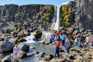 People admiring the waterfall in Thingvellir National Park.