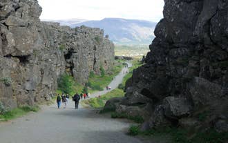 Tourists walking across the rift valley at Thingvellir National Park.