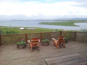 Two wooden chairs on a terrace overlooking a lake.