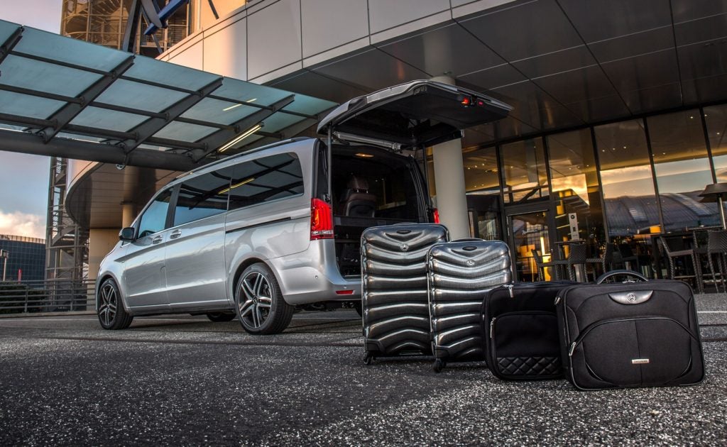 A luxury vehicle with two suitcases outside it, ready for an airport transfer.