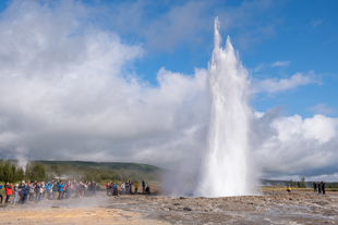 Travelers watch in awe as the Golden Circle's Strokkur geyser shoots superheated water into the air.