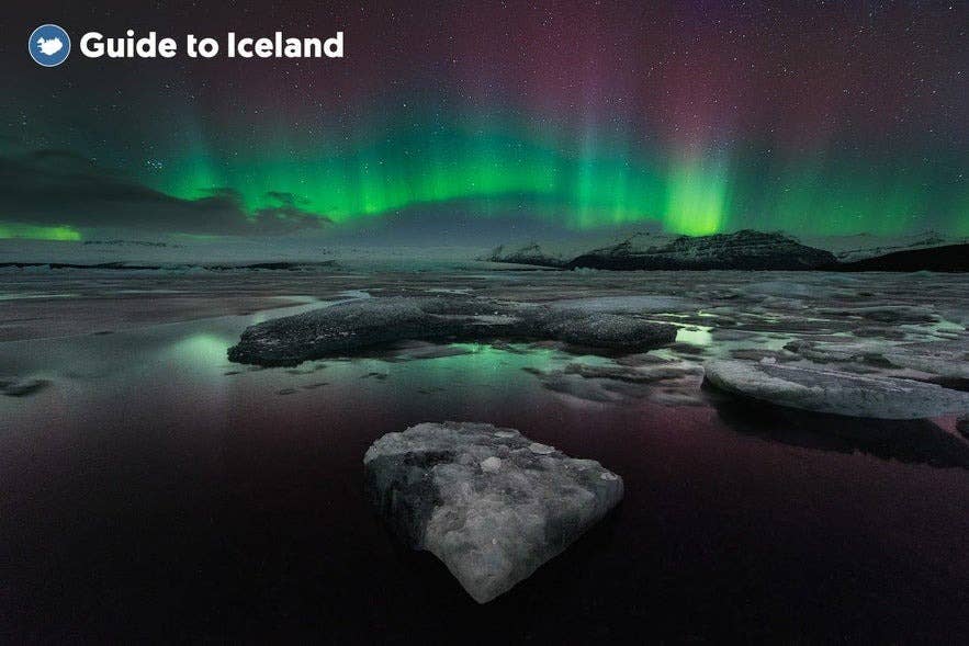 Jokulsarlon glacier lagoon with northern lights and floating icebergs reflecting green and purple aurora in Iceland