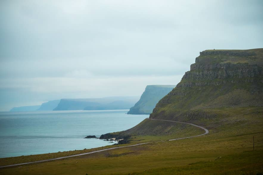 Low cloud over a fjord road in the Westfjords, where summer weather turns quickly and snow closes mountain passes.