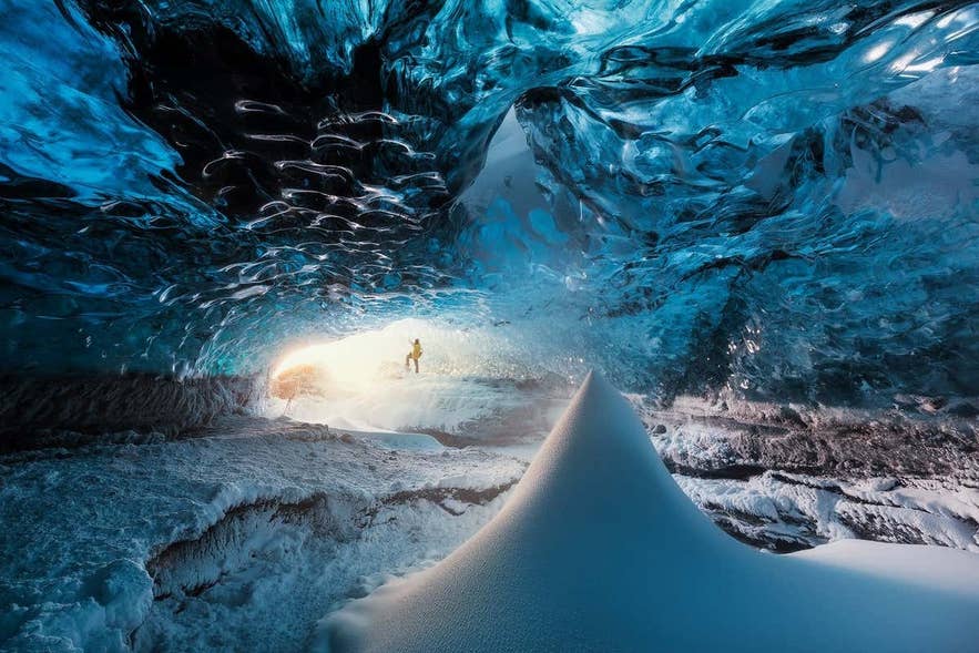 Traveler inside a blue ice cave in Iceland, an experience available only during the Icelandic winter.