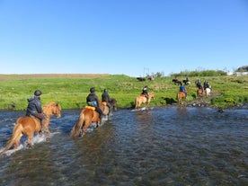 A group of people cross a river on horses.