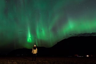 A display of northern lights illuminates the mountainous landscapes of Iceland.