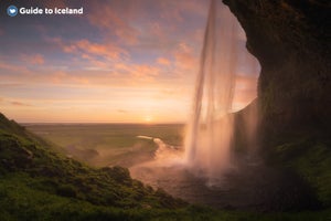 La cascada Seljalandsfoss en la Costa Sur de Islandia, bañada por el impresionante sol de medianoche.