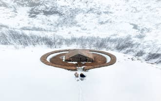 A couple stands in front of an old farmstead in Iceland.