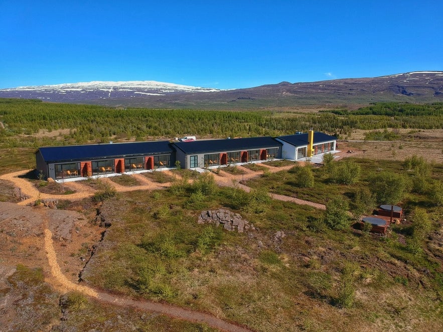 Hotel 1001 Nott near Studlagil Canyon, a scenic retreat in East Iceland with forest views, mountain backdrop, and private outdoor tubs.