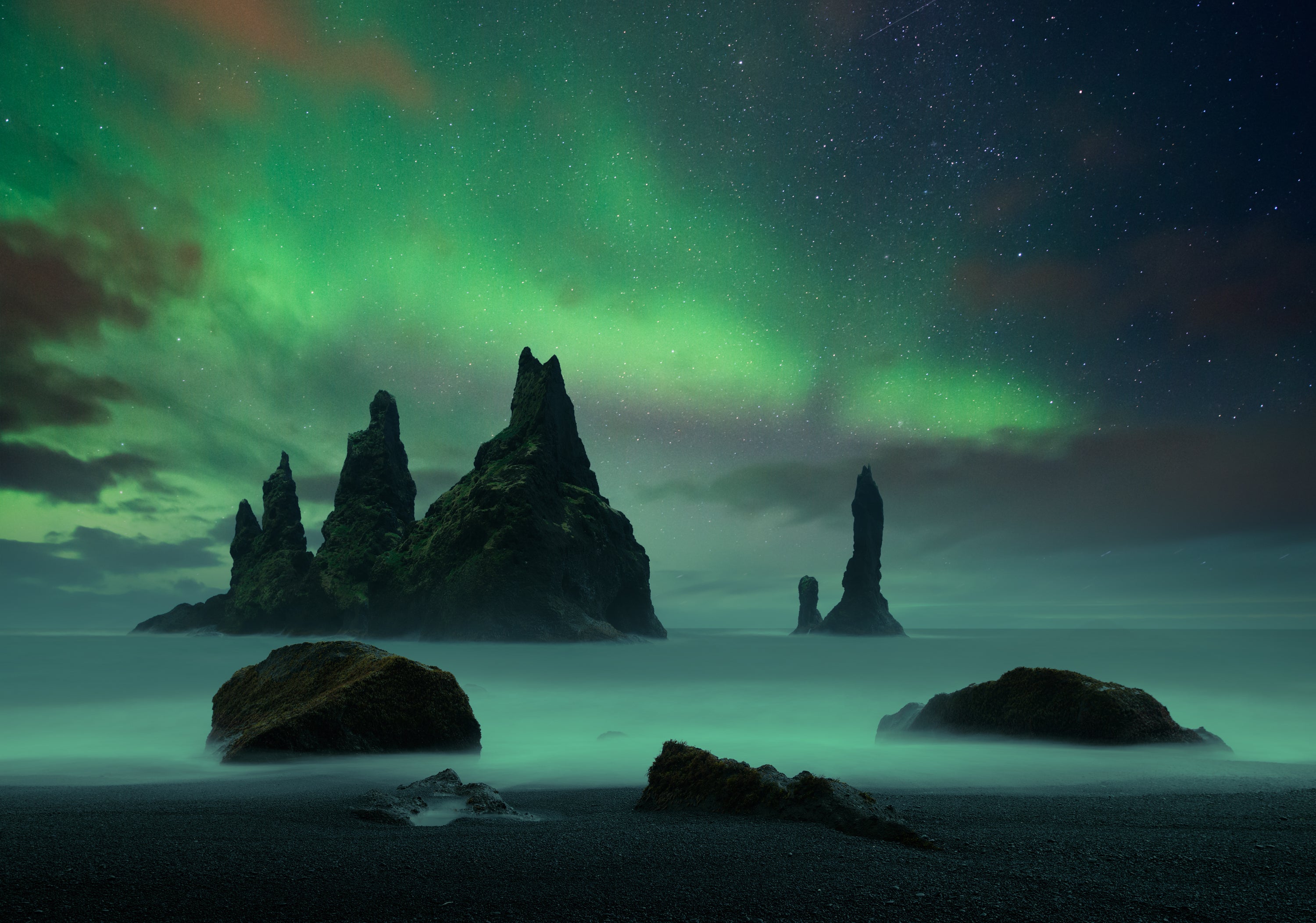 The northern lights seen dancing above the black sand beach of Reynisfjara.