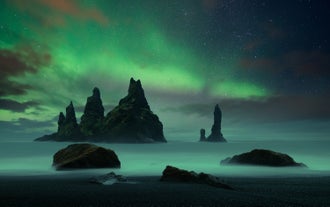 The northern lights seen dancing above the black sand beach of Reynisfjara.