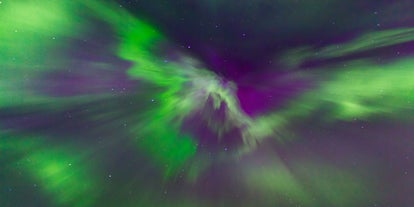 The northern lights showcase a display of greens, purples, and reds in the night sky.