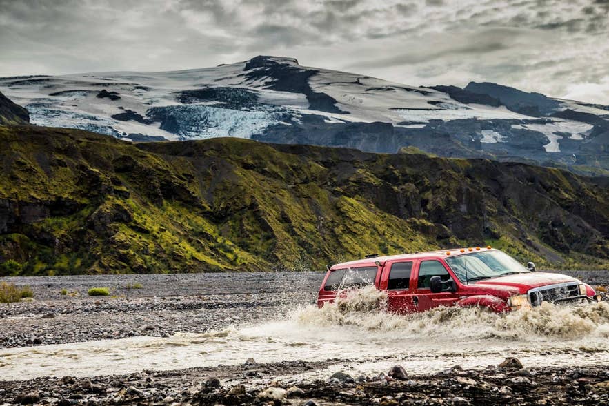 Four-wheel-drive vehicle fording a rocky river crossing in Iceland.