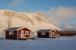 Outside view of Moar Cottage blanketed in snow, with towering mountains in the background.