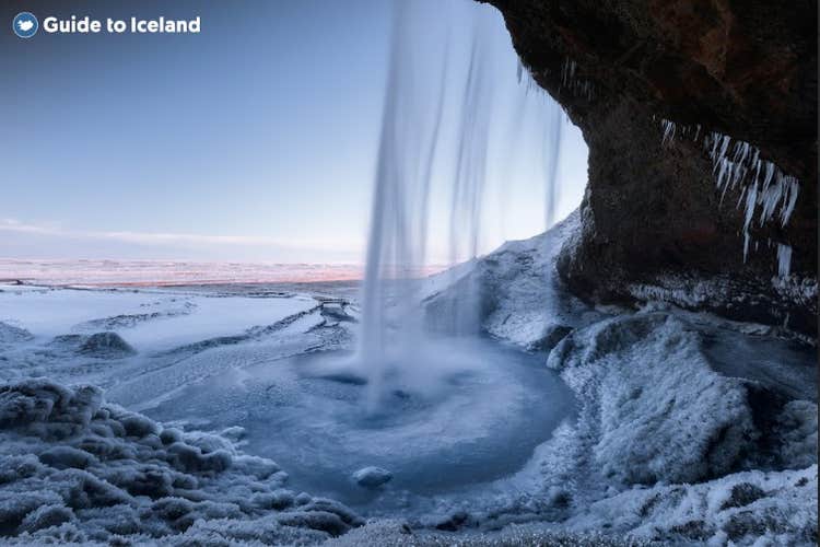The Seljalandsfoss waterfall is surrounded by snow in winter.