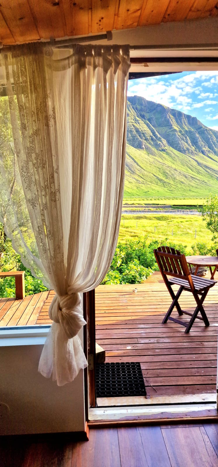 A decking area outside a house surrounding by mountains in Iceland.