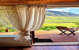 A decking area outside a house surrounding by mountains in Iceland.