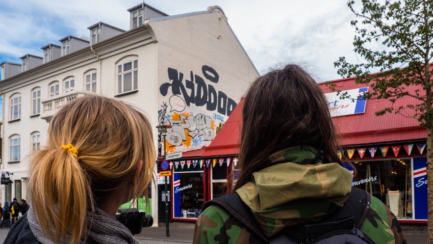 Travelers walking past souvenir shops and street art in downtown Reykjavik, Iceland