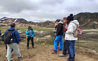 A guide explains the landscape to a group of hikers during a Landmannalaugar tour.
