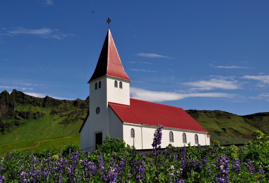 Vík Church is a quaint white church with a red roof on a hill