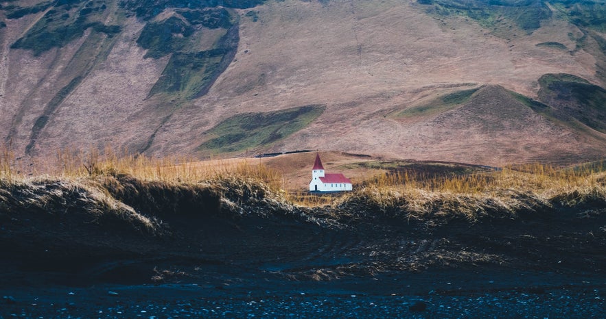 Reyniskirkja in Iceland set against rugged hills.