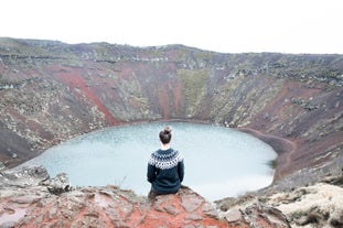 A traveler sits at the rim of Kerid crater along the Golden Circle of Iceland.