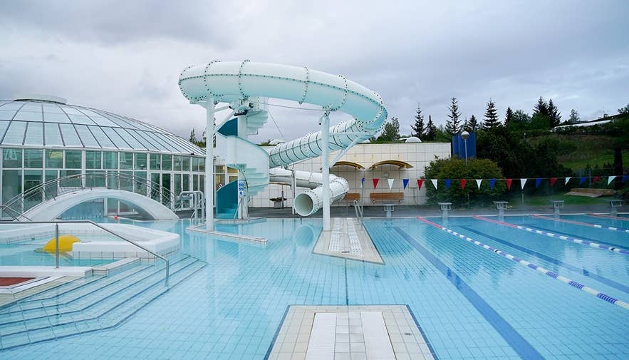 Water slide and glass-domed indoor pool at Arbaejarlaug, one of Reykjavik's popular swimming pools for indoor activities on a rainy day.