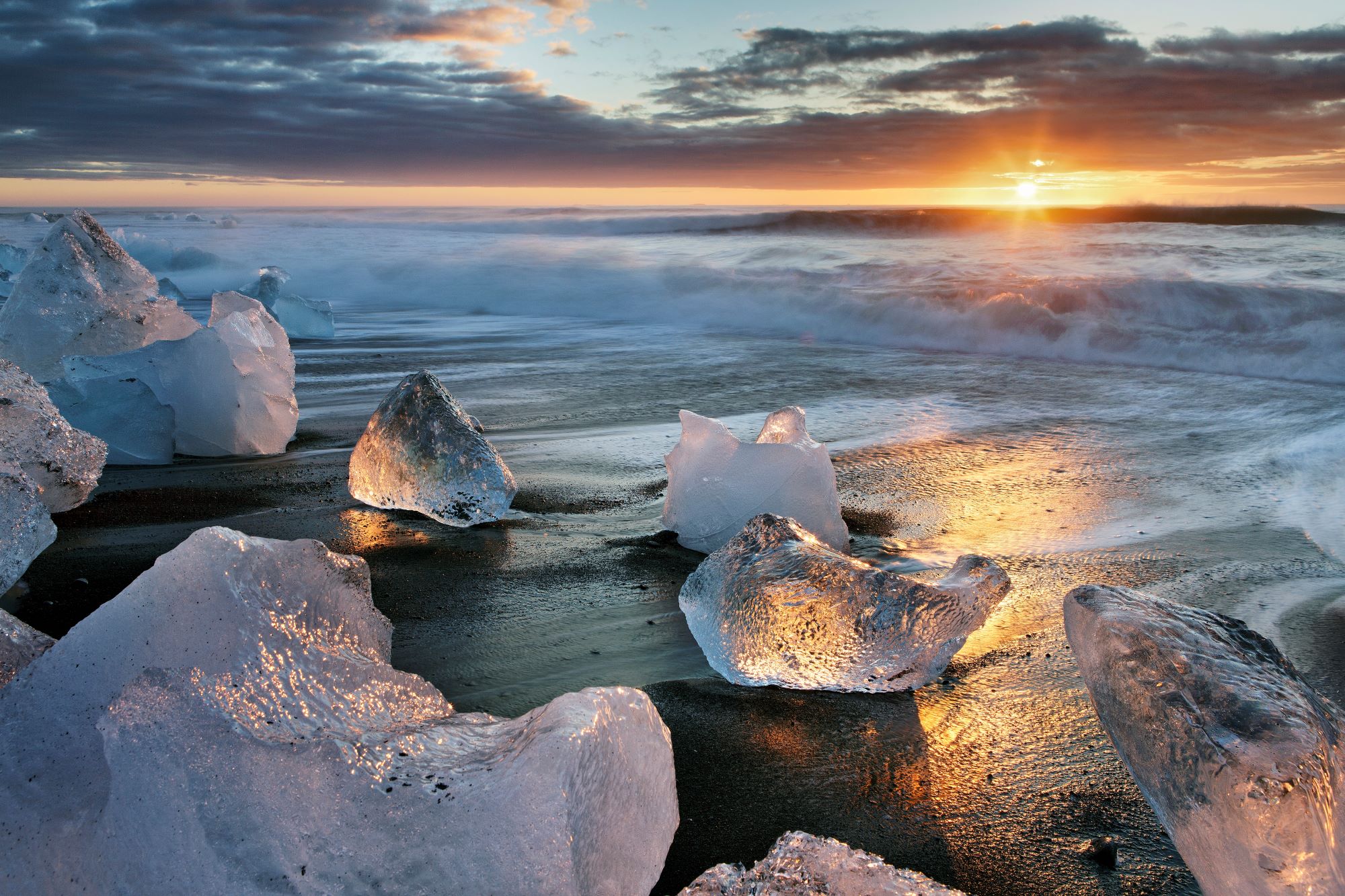 Los icebergs brillan al sol en la playa de arena negra.