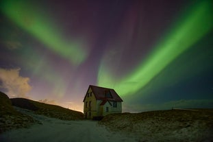 The northern lights dance above a solitary house in Iceland.