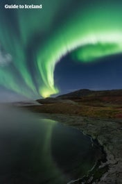 Northern lights swirl over a hot spring in North Iceland.