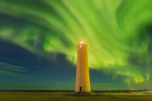 A beautiful display of aurora borealis shines above a lighthouse in Iceland.