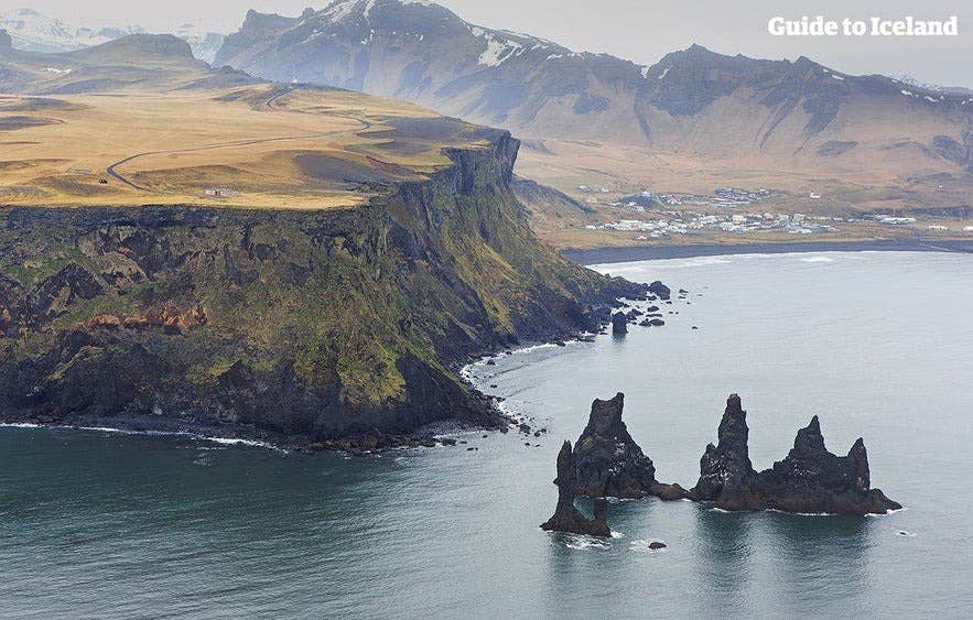 Aerial view of Reynisdrangar sea stacks near the cliffs of Reynisfjall in Vík í Mýrdal, South Iceland, with dramatic coastline and volcanic landscape.