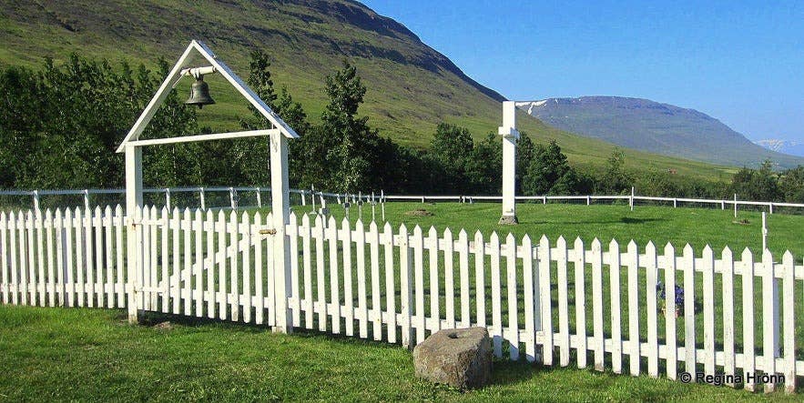 Modern graveyard by the Myrka River in North Iceland, enclosed by a white picket fence with a bell gate, set against a mountainous summer landscape. Modern graveyard by the Myrka River in North Iceland, enclosed by a white picket fence with a bell gate, set against a mountainous summer landscape.