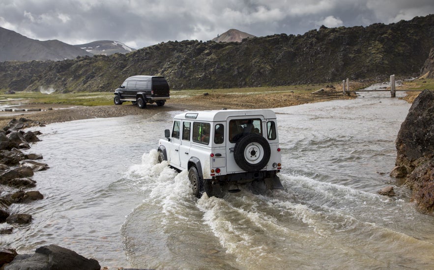 A convoy of jeeps cross a river in Iceland.