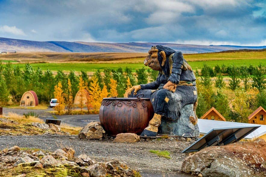 Statue of Icelandic Christmas troll Gryla stirring her cauldron in West Iceland, surrounded by autumn countryside and turf-style cabins. Statue of Icelandic Christmas troll Gryla stirring her cauldron in West Iceland, surrounded by autumn countryside and turf-style cabins.
