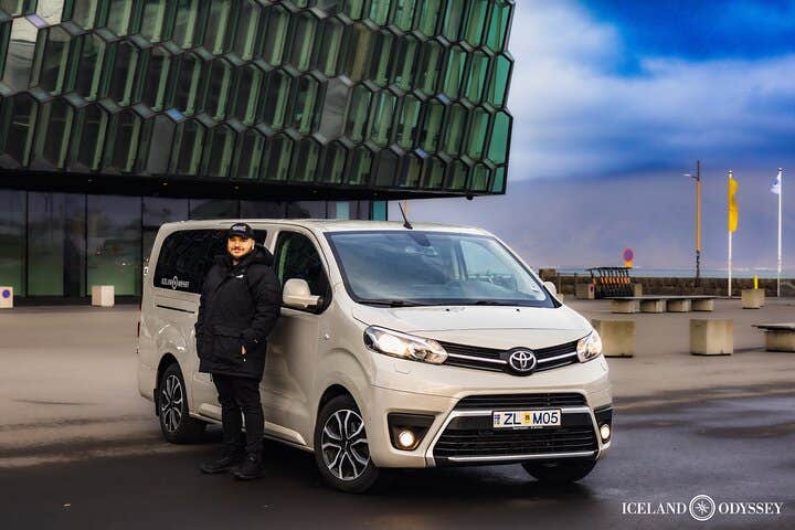 A tour guide stands outside a minibus on a Golden Circle tour in Iceland.