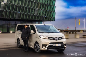 A tour guide stands outside a minibus on a Golden Circle tour in Iceland.