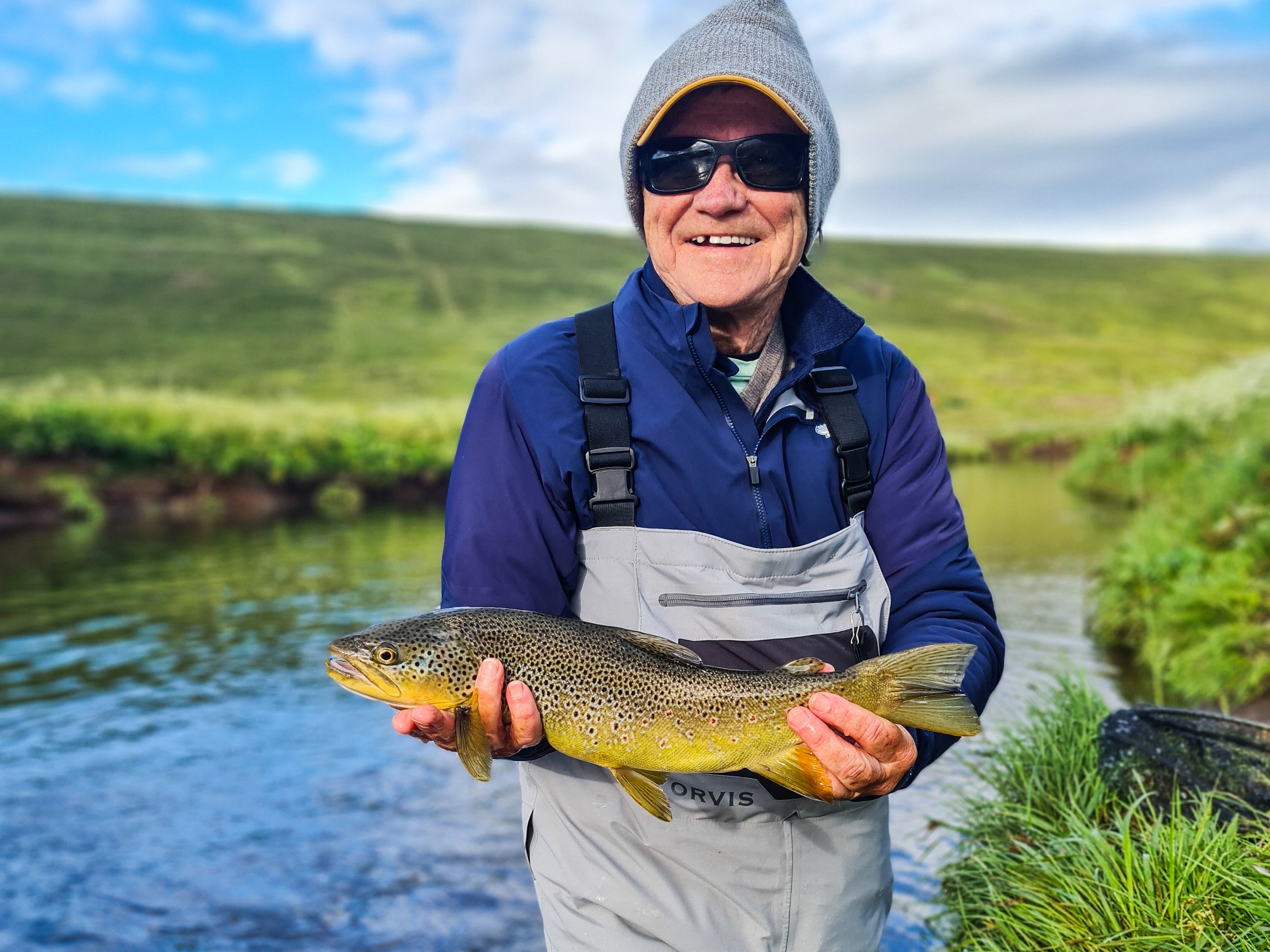 A happy tour joiner holds a fish during a full day fishing tour in North Iceland.