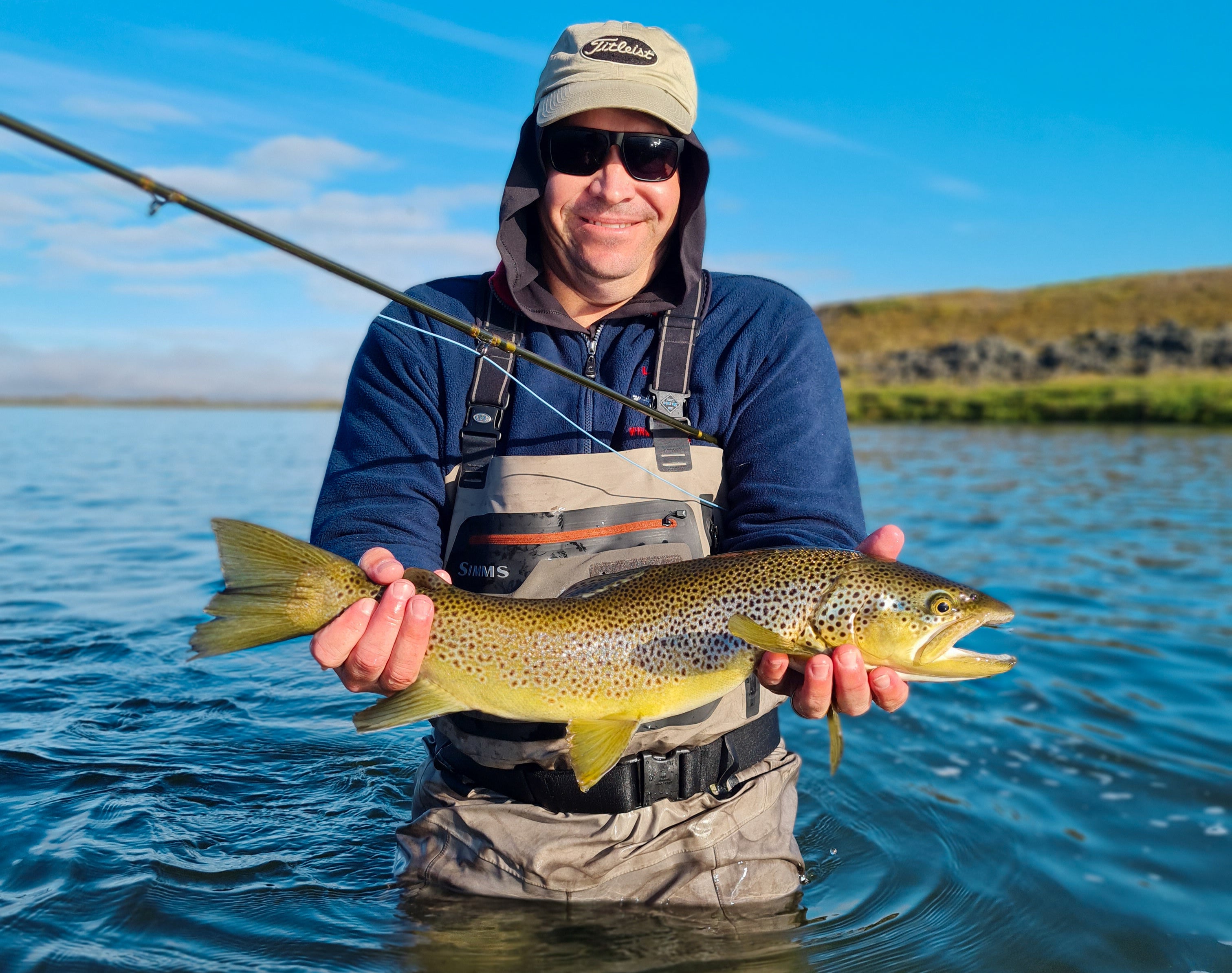 An angler holding a brown trout during a fishing tour in North Iceland.